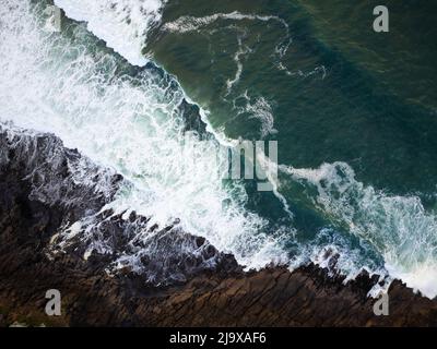 View from above. Storm in the ocean, sea. Dark turquoise water with white foamy waves breaks on the rocks on the shore. Background. Wallpaper. Texture Stock Photo