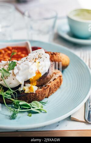 Healthy breakfast from poached eggs, grilled halloumi, Scrambled smoked harissa tofu, smashed avocado, grilled mushrooms and tomato beans on toast Stock Photo