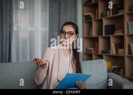 Smiling confident young european woman doctor psychologist in glasses with tablet gesturing with hands Stock Photo