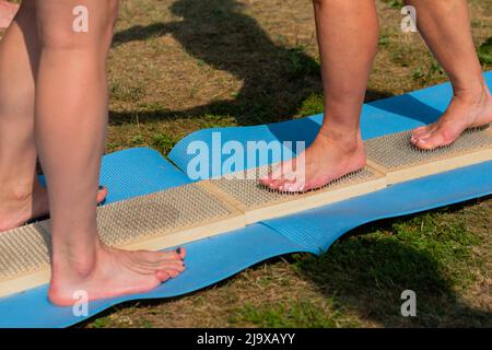Woman feet walking barefoot on wooden boards with sharp nails at yoga festival Stock Photo