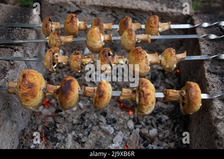 Preparing mushrooms on burning coals. BBQ for vegetarians. Stock Photo
