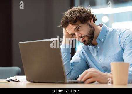 Sad business man leaning head on hand using pc Stock Photo