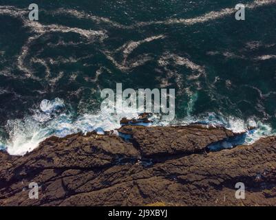 Shooting from the air. Turquoise ocean water with white light waves and rocky shore. Seascape. Place for recreation, water sports, fishing. Travel, to Stock Photo