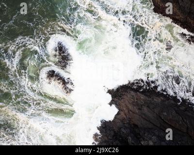 Aerial view of the sea tide. Storm in the ocean. White foamy waves break on the rocky shore. The power and majesty of nature. Weather, geology. Touris Stock Photo