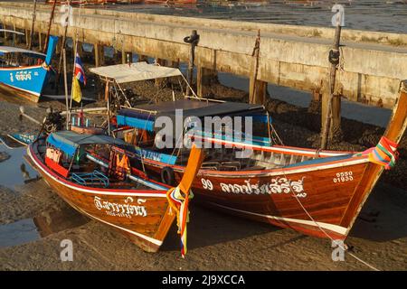 Colorful Thai fishing boats sitting on the bottom of the sea during low tide in Koh Muk island Stock Photo