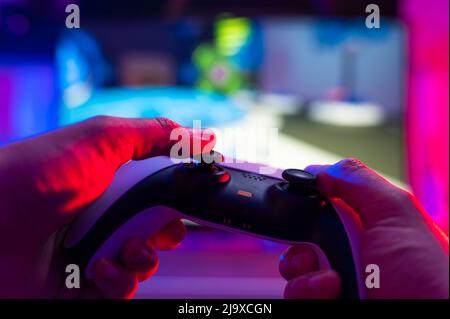 Close-up. The gamer holds a gamepad in his hands. Plays video