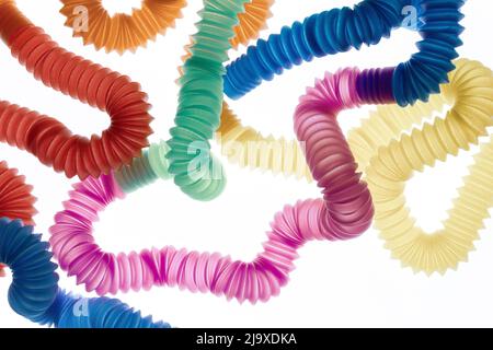 Trendy kids toys — colorful pop tubes on white background. Set of different forms and colors corrugated pipe. Stock Photo