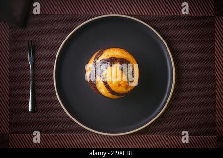 Vanilla Muffin with chocolate marbled on brown paper isolated on a thin plate on a nice table, fine pastries Stock Photo