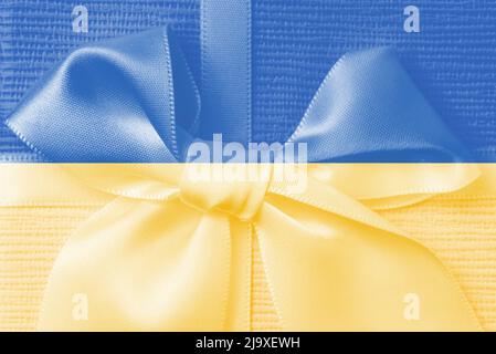 Photo toning in yellow and blue. Soft selective focus on a bright bow with satin ribbon on a gift box. Concept of support for Ukraine, State flag. Stock Photo