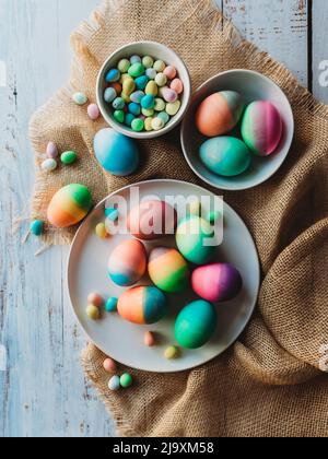 Assortment of brightly colored easter eggs on burlap and white wood. Stock Photo