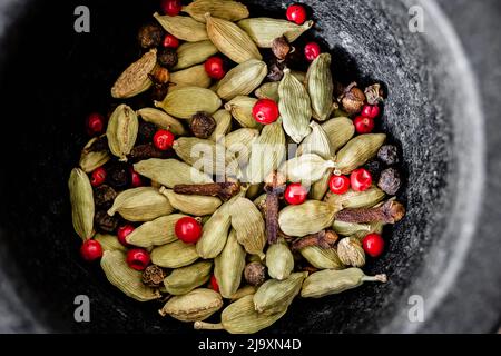 Cardamom and pepper in a black bowl. Stock Photo
