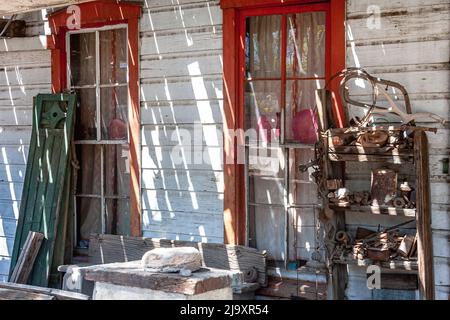 Junk stored on the side of a store at Madrid, NM. Two long windows and streaks of light and shadows. Stock Photo