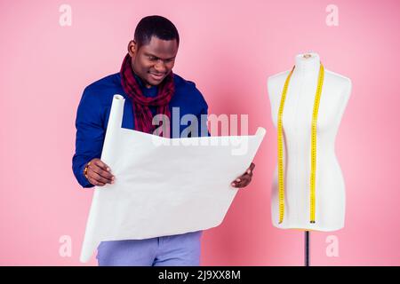 African American man tailor seamstress workshop stylish male model clothes designer measuring tape on neck posing next to the mannequin looking at the Stock Photo