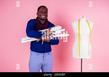 African American man tailor seamstress workshop stylish male model clothes designer posing next to the mannequin on pink background in the studio Stock Photo