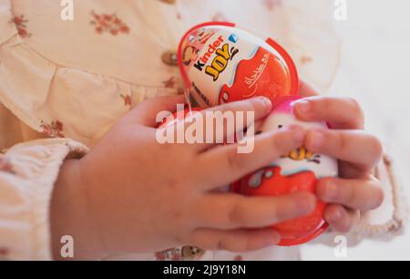 Cairo Egypt. 22. April 2022 Small girl holds chocolate Kinder Surprise Egg. Tasty chocolate present for child. sweet tooth. Stock Photo