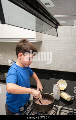 8 year old in the kitchen making a Brazilian sweet, brigadeiro (brigadier). Stock Photo