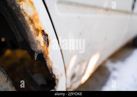 Rusted fender of a white car close-up. The effect of reagents in winter on an unprotected car body. rotten metal Stock Photo