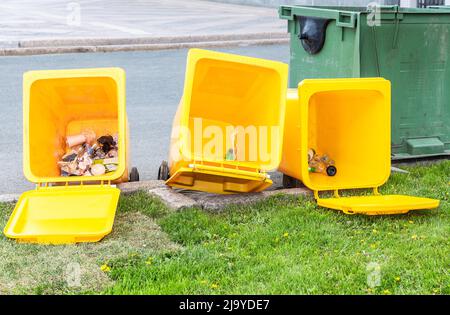 Overturned yellow plastic trash containers lie on the city street Stock Photo