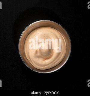 Spicy sauce in a metal gravy boat on a black background for fast food Stock Photo