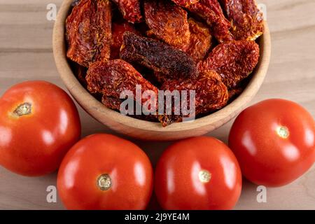 Fresh tomatoes and sun dried tomatoes with on wooden background Stock Photo
