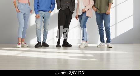 Cropped shot of legs of young unrecognizable stylish people who are standing in row. Stock Photo