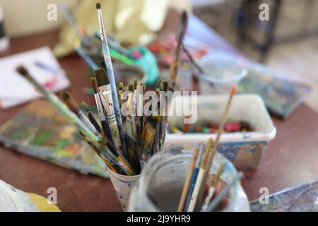 Glasses with brushes for painting at artist workplace Stock Photo