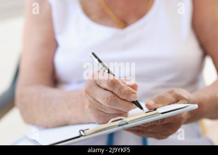 Hands of old woman with sheet for writing text Stock Photo