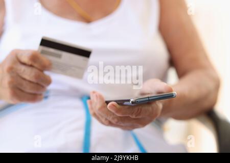 Elderly woman makes purchases on Internet on smartphone and pays with credit card Stock Photo