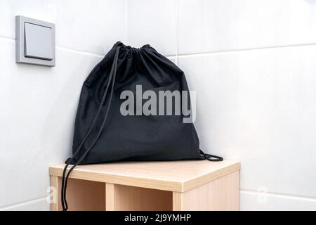 Black fabric bag on a shelf at a bathroom, bag for keeping accessories, hair dryer Stock Photo