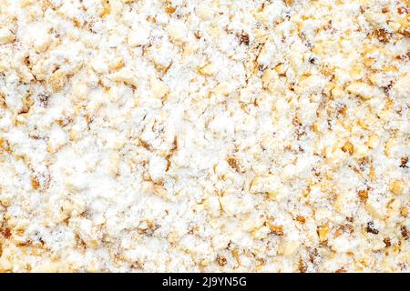 Part of sweet cake with white powder, cream and broken nuts, top view as texture, background and space for text Stock Photo