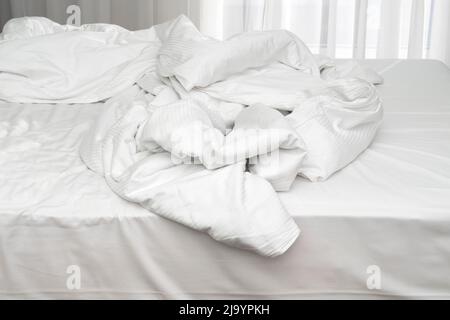 Morning time in hotel, unmade bedding  linen, mess with pillows, sheets, blanket Stock Photo