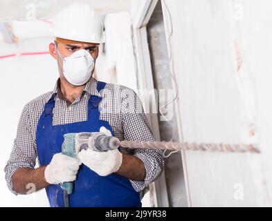 Portrait of repairer male working with drill indoors Stock Photo