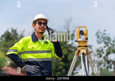 Surveyor Civil Engineer using the phone with equipment theodolite or total positioning station on the construction site. Stock Photo