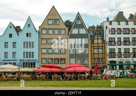 Cologne, Germany - May 17, 2022 : View of people sitting at an outdoor terrace restaurant and colourful traditional residential buildings in the backg Stock Photo
