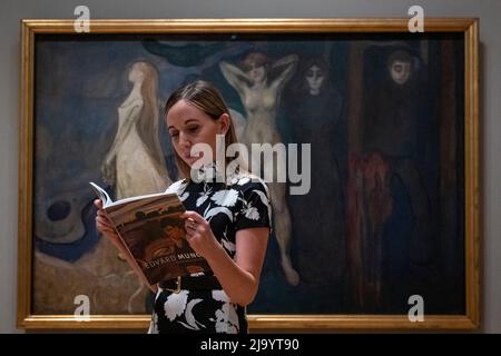 London, UK.  26 May 2022. A staff member views a brochure in front of 'Woman in three stages', 1894, by Edvard Munch at the preview of “The Morgan Stanley Exhibition: Edvard Munch. Masterpieces from Bergen” at The Courtauld Gallery.  18 paintings by Munch from KODE Bergen Art Museum, Norway, home to one of the most important Munch collections in the world are shown together as a group outside Scandinavia for the first time.  The exhibition runs 27 May to 5 September 2022.  Credit: Stephen Chung / Alamy Live News Stock Photo