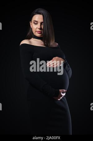 portrait of pregnant woman in black dress on black background