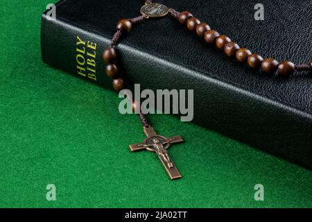 Bible with crucifix and rosary on a green felt surface Stock Photo