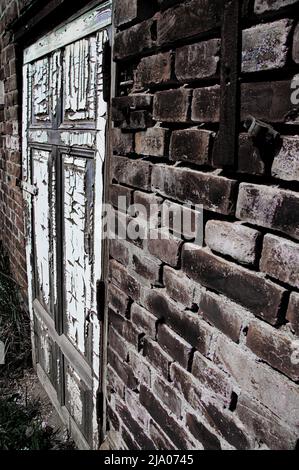 Mystical old door in a brick wall. The remnants of the ghetto give way to new development. The secret behind the door. Stock Photo