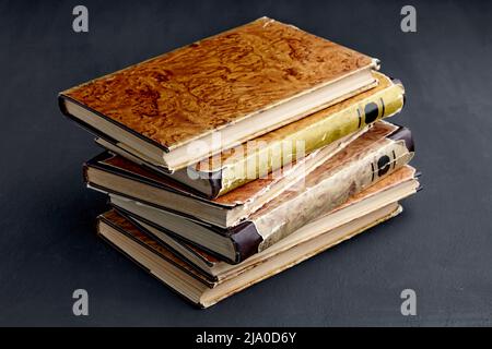 Stack of vintage dilapidated books on a dark concrete table Stock Photo
