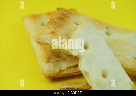 Two sides of a delicious square cracker, isolated on yellow background Stock Photo