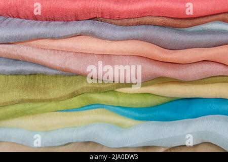 Stack of colorful silk soft fabrics folded, abstract striped textile background. Stock Photo