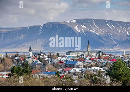 Reykjavik, Iceland, April 25, 2022: View from Öskjuhlíð hill with Háteigskirkja and Seaman's School rising above the colorful roof, and the mountains Stock Photo