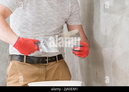 A man with a small spatula applies lime plaster on a large spatula, lime plaster on the walls and ceiling, repair work. Stock Photo