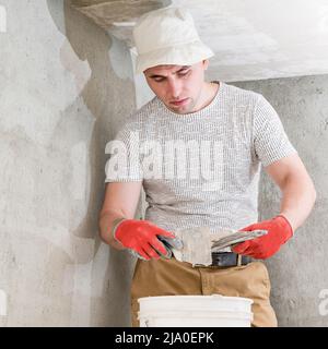 The master works with lime plaster, leveling the wall with a spatula and lime plaster, repairing work on leveling the walls. Stock Photo