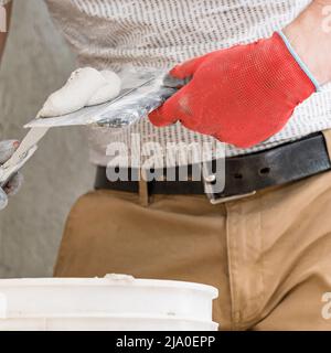 Lime plaster on a spatula, repair and decoration work with lime plaster, two dirty spatulas, lime plaster in a bucket. Stock Photo