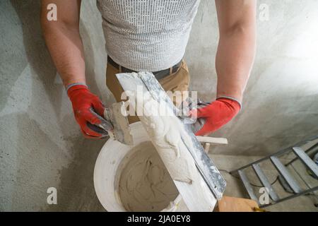 Lime plaster on a spatula, repair and decoration work with lime plaster, two dirty spatulas, lime plaster in a bucket. Stock Photo