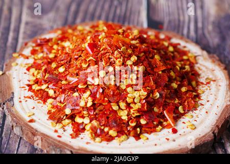 dried peppers flakes on a wooden plate on table  Stock Photo