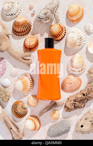 Bottle of sunscreen on background of seashells in hard light, top view. Sun protection lotion flat lay, creative image Stock Photo