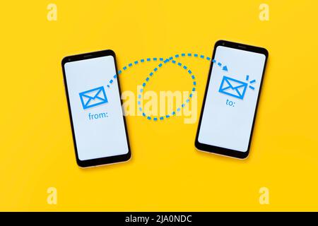 email concept. Two cell phones on a yellow background showing the operation of electronic mail through a drawing. Stock Photo