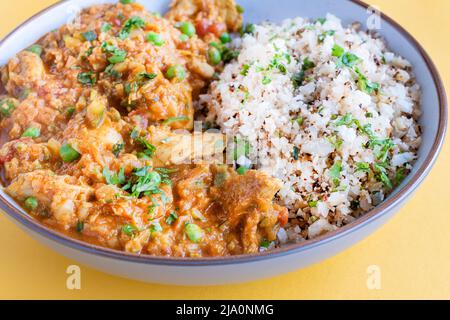 A home made chicken courgette tikka masala curry served in a bowl with cauliflower rice. A healthy protein rich meal choice which is keto friendly Stock Photo